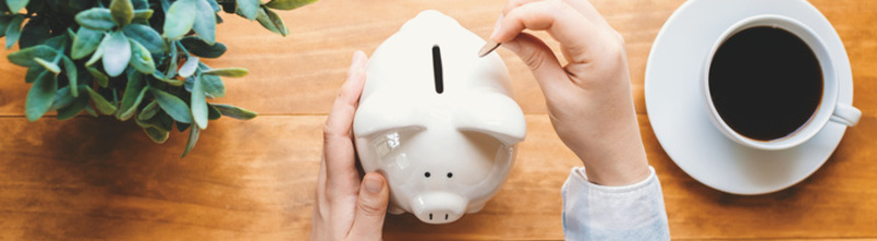 Woman holding a white piggy bank on a wooden desk Woman holding a white piggy bank on a wooden desk